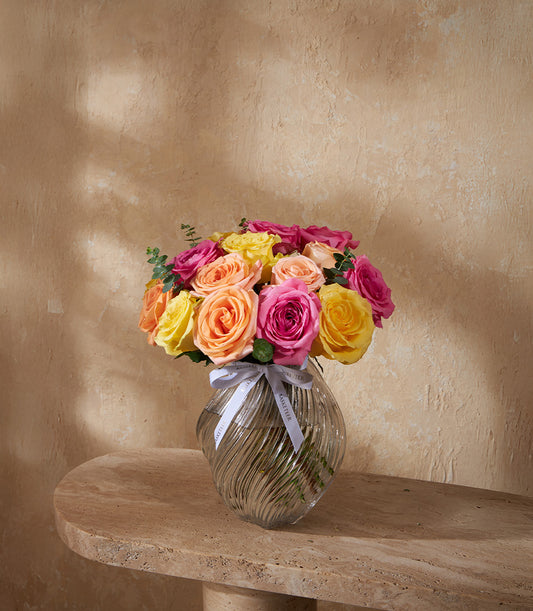 Radiance Trio rose vase with vibrant yellow, orange, and pink roses in clear glass