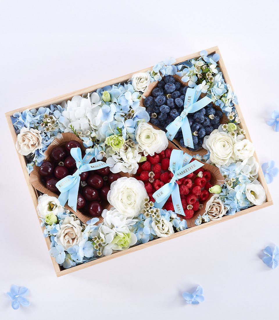 Premium berry and flower gift box with fresh cherries, raspberries, blueberries, and light blue hydrangeas for Mother's Day