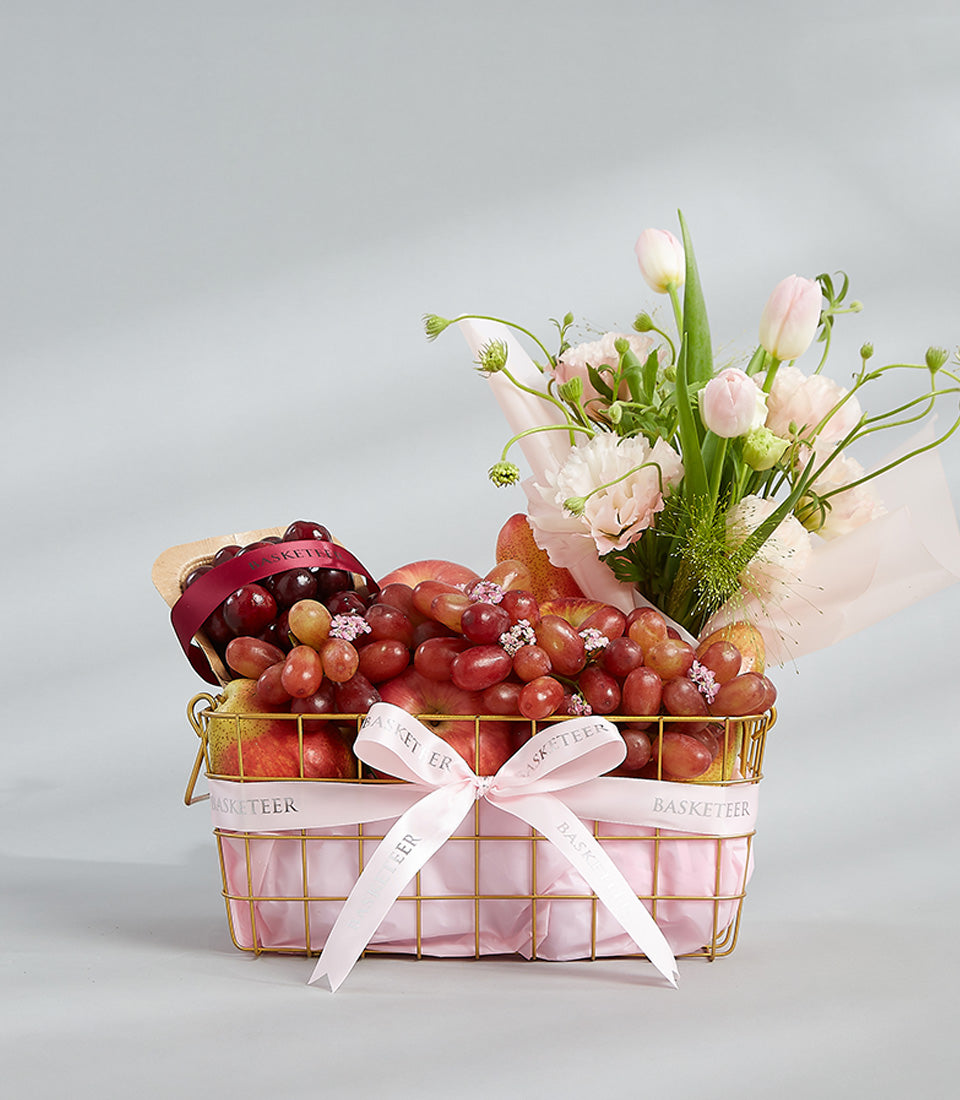 Pink and gold luxury fruit basket with fresh blooms for birthday gifting