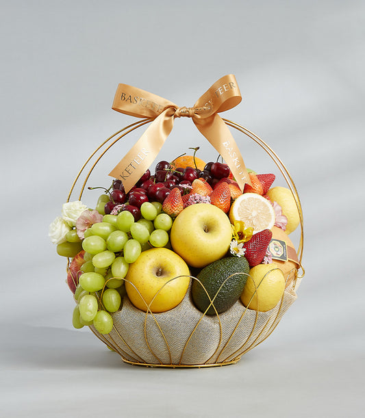Golden Harmony fruit basket with fresh grapes, cherries, strawberries, and apples in gold-toned wire basket with satin ribbon