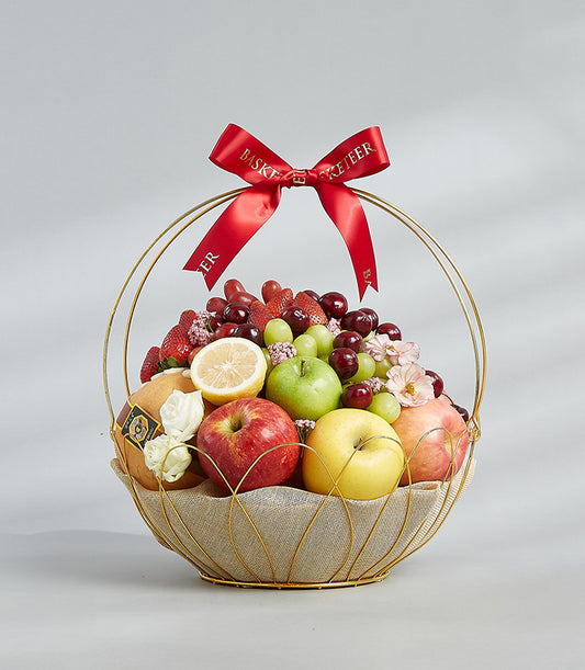 Golden fruit basket with apples, berries, and pears tied with red Basketeer ribbon