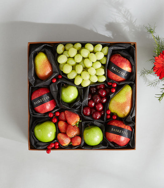 Assorted fresh fruit gift box with grapes, apples, pears, cherries and strawberries in luxury compartmented presentation