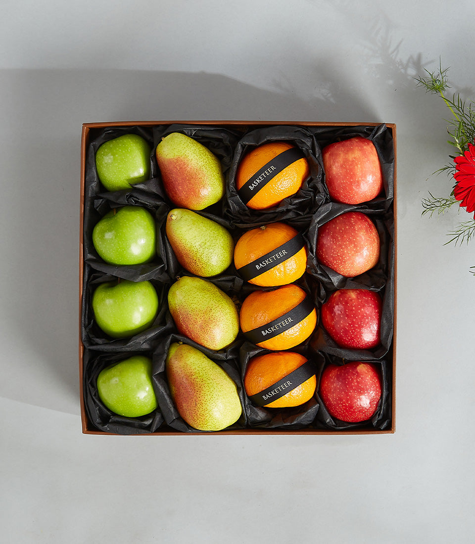 Luxury fruit gift box with green apples, pears, and ribbon-wrapped oranges in black tissue compartments