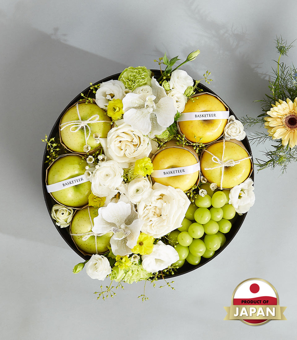 Luxury Japanese fruit gift box with fresh apples, grapes, and white roses in elegant black round container