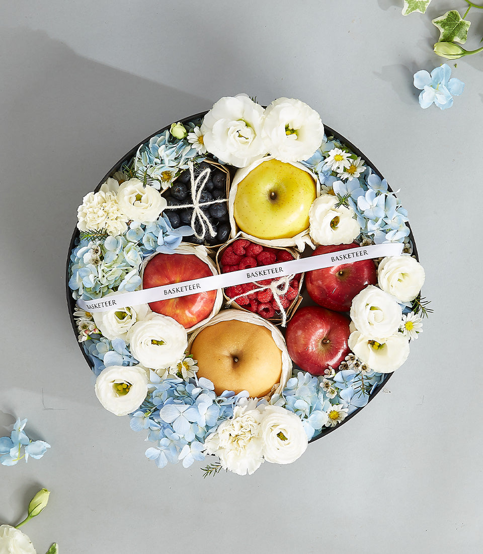 Luxury mixed fruit and fresh flower gift basket with apples, pear, berries, hydrangeas and ranunculus