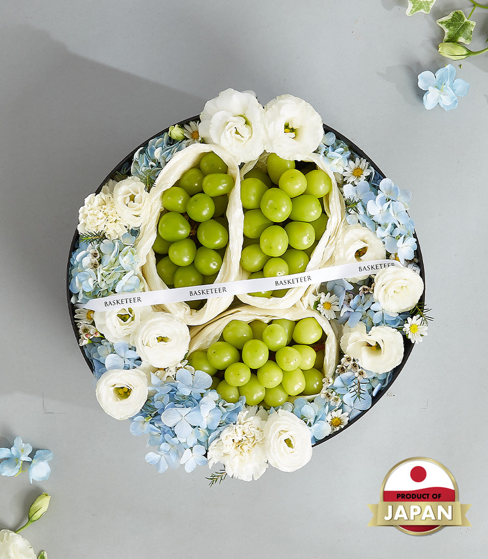 Premium Japanese green grapes in luxury round gift box with white roses and blue hydrangeas