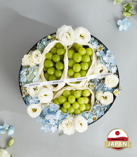 Premium Japanese green grapes in luxury round gift box with white roses and blue hydrangeas