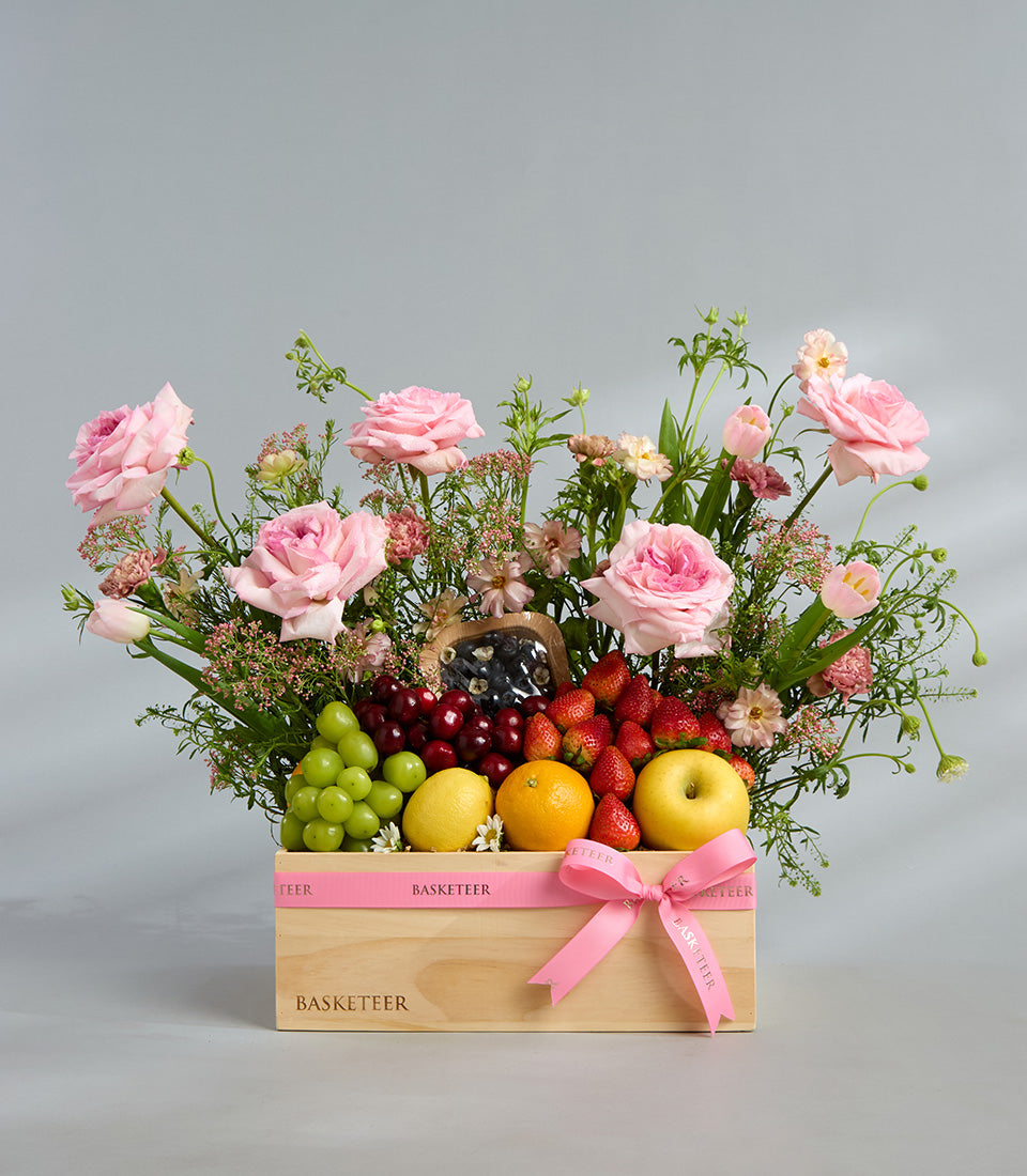 Romantic pink floral and fresh fruit wooden gift basket with roses, tulips, berries, and citrus