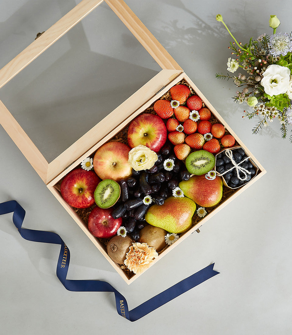 Premium wooden fruit box with fresh apples, kiwis, grapes, strawberries, and blueberries, decorated with white flowers