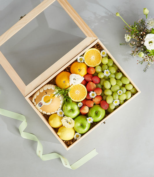 Luxury wooden fruit box with fresh citrus, grapes, strawberries, and artisan tart, adorned with white flowers