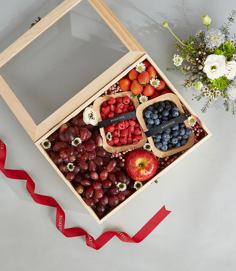 Luxury mixed fruit gift box with red grapes, apple, strawberries, raspberries, and blueberries in wooden case