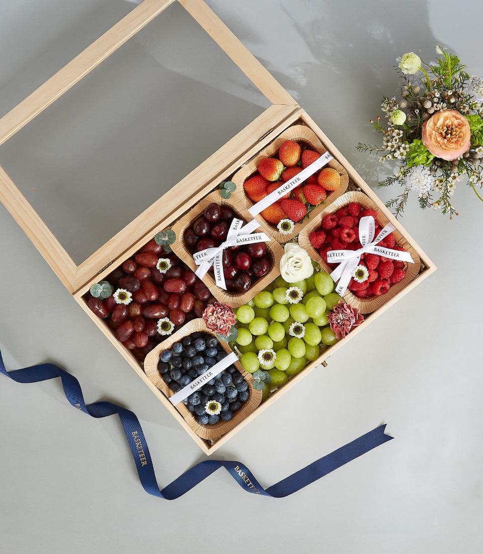 Luxury wooden fruit box with fresh berries, grapes, cherries, blueberries, strawberries and raspberries in biodegradable