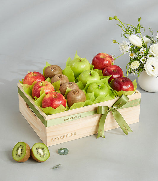 Wooden crate of fresh red and green apples with kiwis in light green tissue, tied with Basketeer ribbon bow