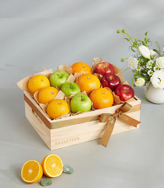 Wooden crate of fresh apples and oranges with gold ribbon bow, premium fruit gift box