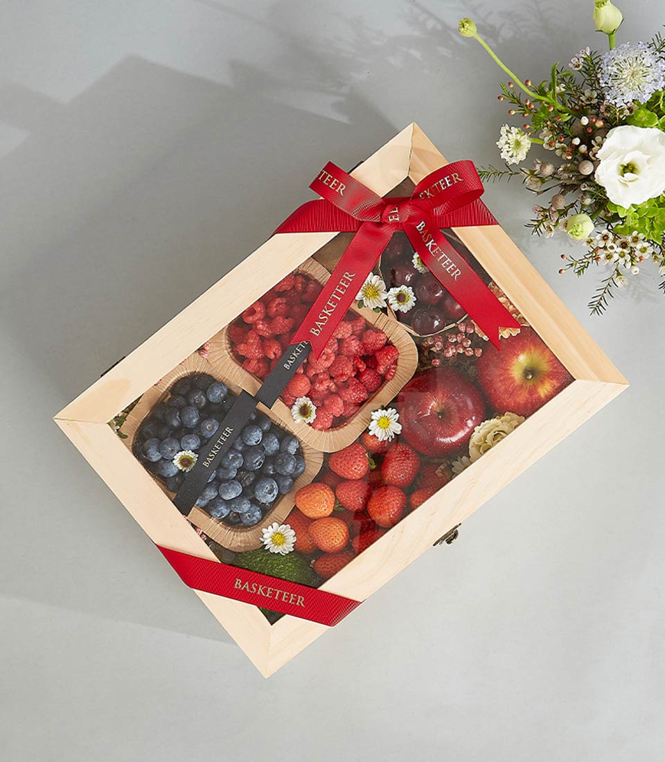 Deluxe wooden fruit crate with fresh berries, strawberries, apples and cherries, red ribbon bow, birthday gift hamper