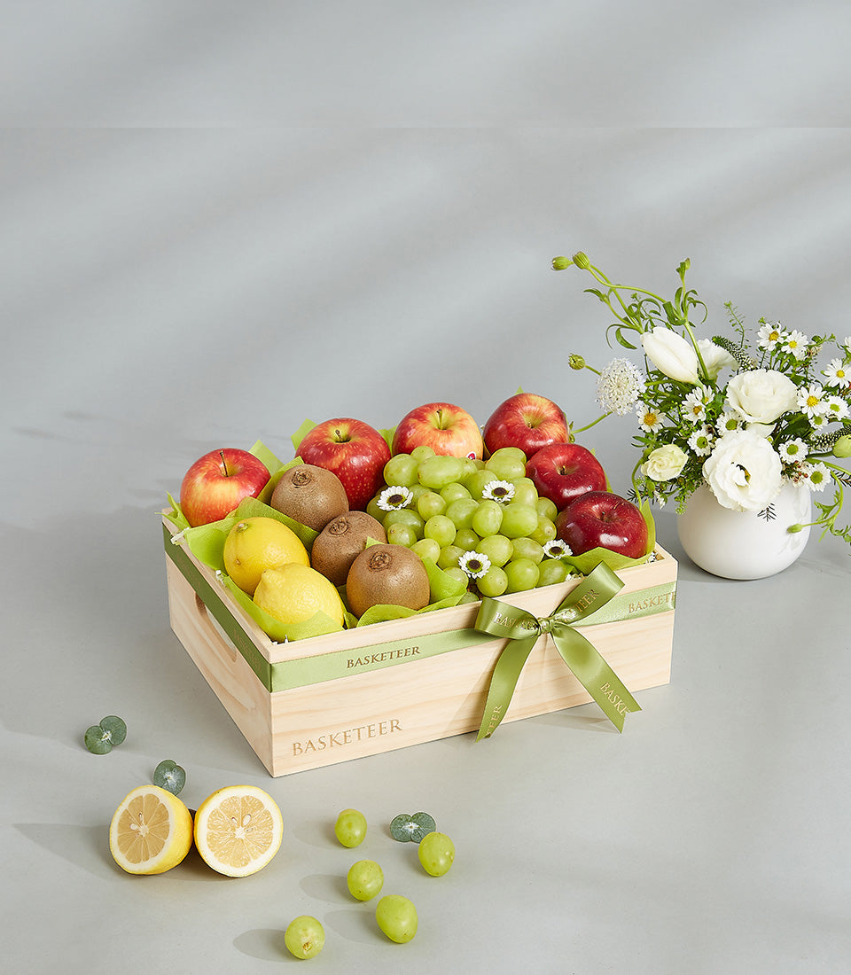 Deluxe mixed fruit gift crate with apples, grapes, kiwis and lemons in light wood box with green ribbon