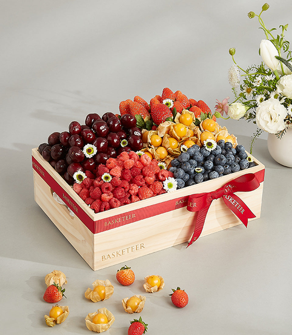 Luxury fresh berry assortment in wooden crate with cherries, raspberries, blueberries, and physalis for birthdays
