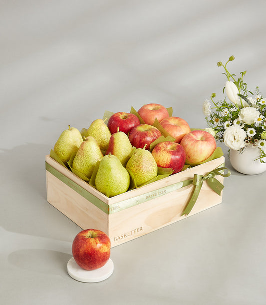 Elegant wooden fruit basket with red apples and pears, tied with green ribbon