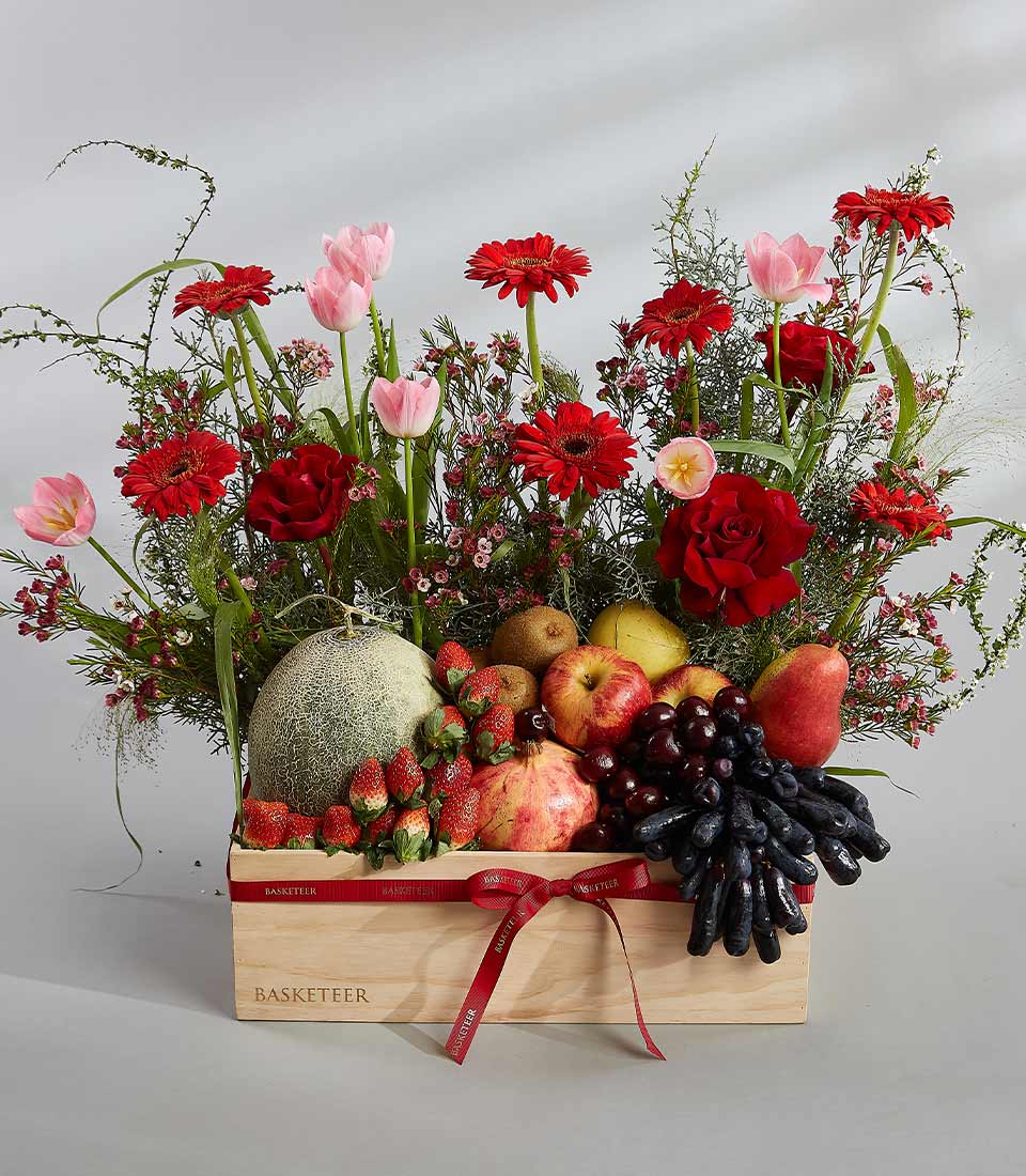 Luxury wooden gift box with red satin bow overflowing fresh strawberries, apples, pears, grapes, vibrant red gerberas,