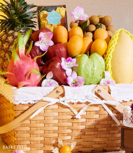 Tropical fruit gift basket with dragon fruit, pineapple, mangoes, and fresh orchids in woven basket