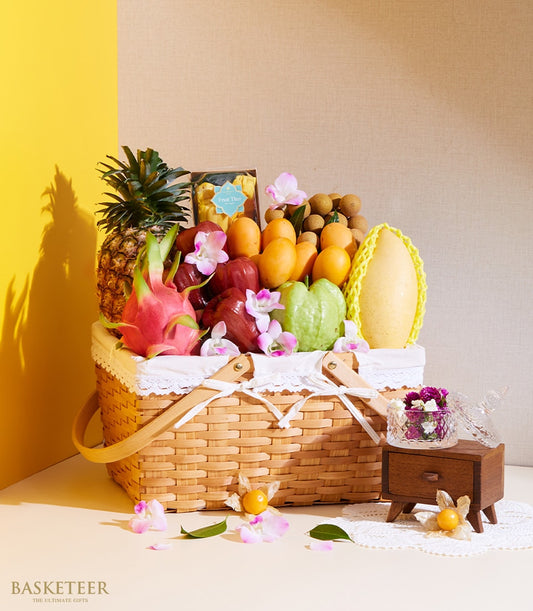 Woven wicker basket filled with tropical fruits, pineapple, dragon fruit, mangoes, and pink orchid flowers