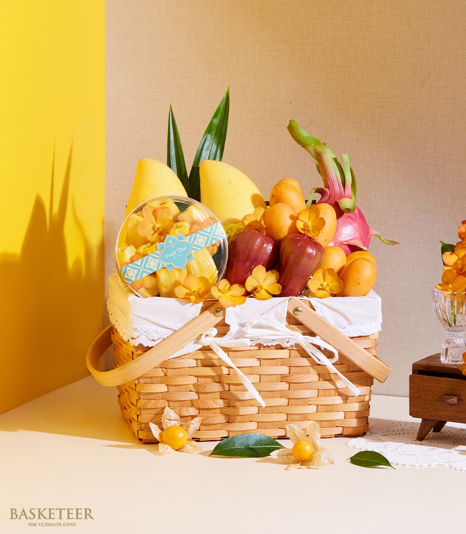 Woven wicker fruit basket with tropical mangoes, dragon fruit, rose apples, and dried jackfruit, adorned with orchids