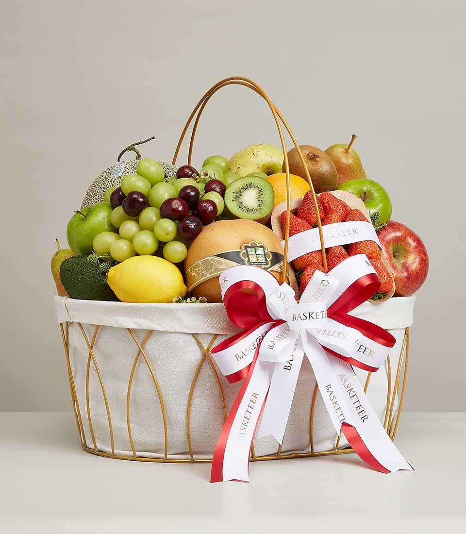 Luxury fruit gift basket with fresh apples, grapes, cherries, and strawberries in white and gold-handled basket