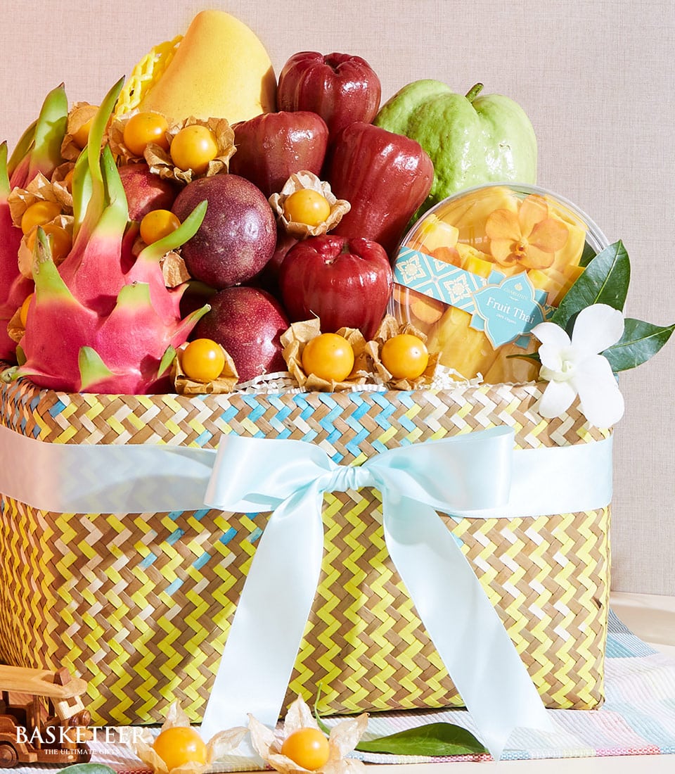 Vibrant tropical fruit basket with dragon fruit, mango, and passion fruit in woven natural fiber with blue satin bow