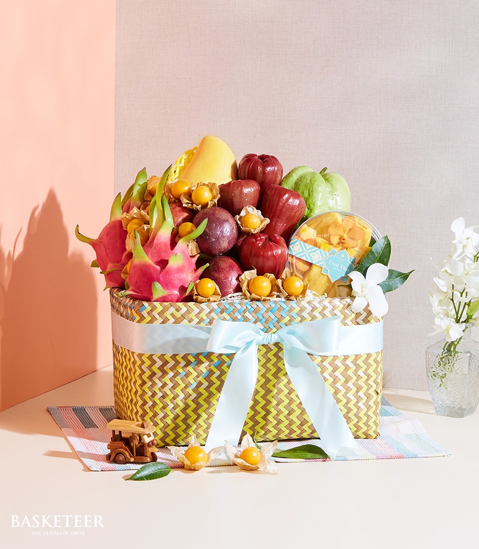 Vibrant Thai tropical fruit basket with dragon fruit, mango, rose apples, and passion fruit in woven yellow and blue gift