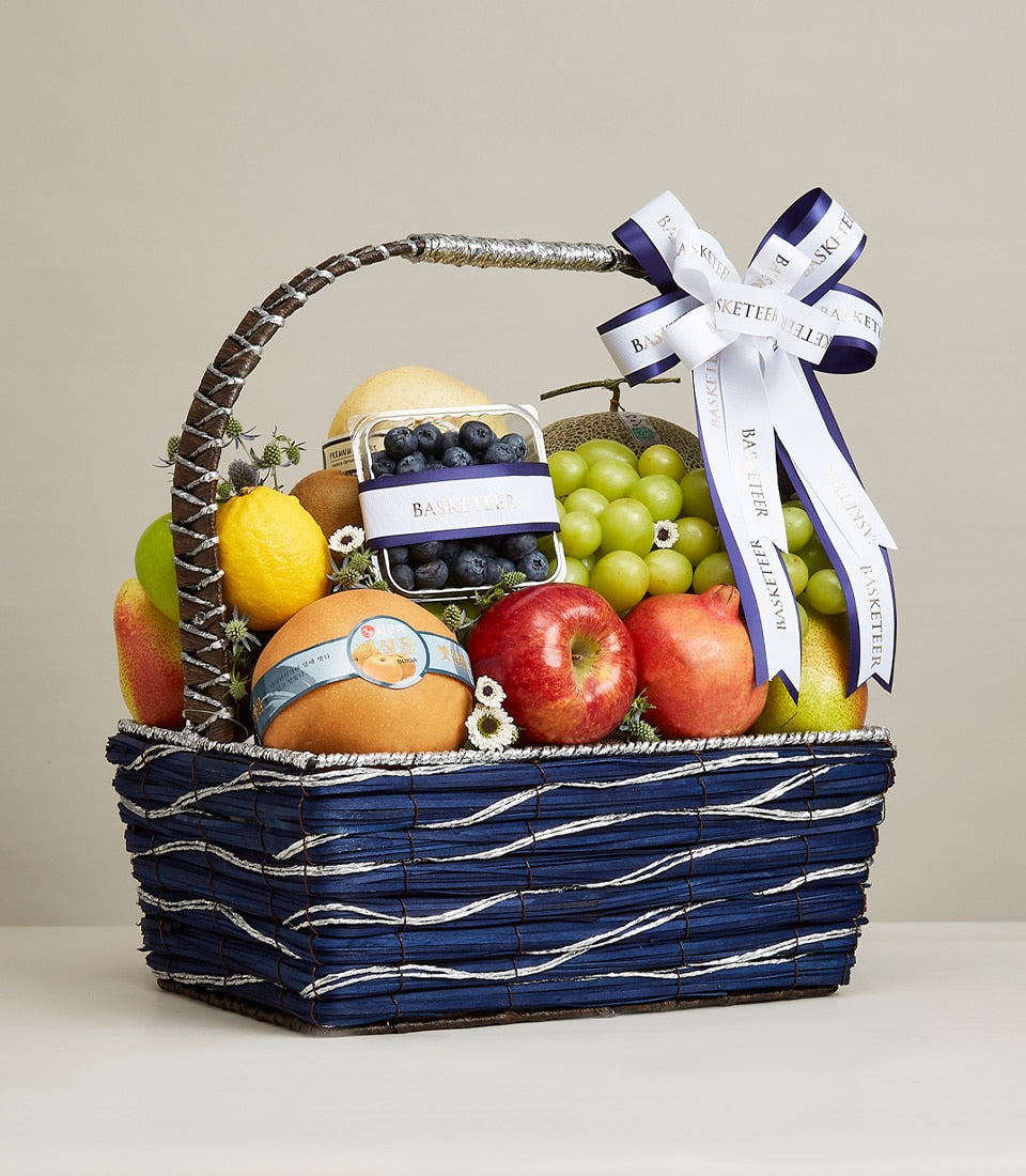 Striped dark blue woven fruit gift basket with fresh apples, pears, grapes, pomegranates, and blueberries for birthdays