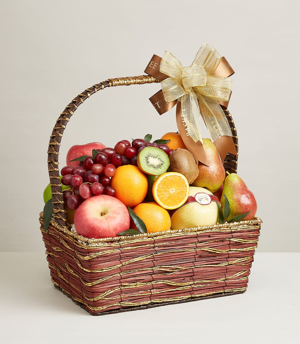 Dark brown wicker fruit basket with gold accents, filled with fresh grapes, apples, oranges, kiwis and pears, tied with gold