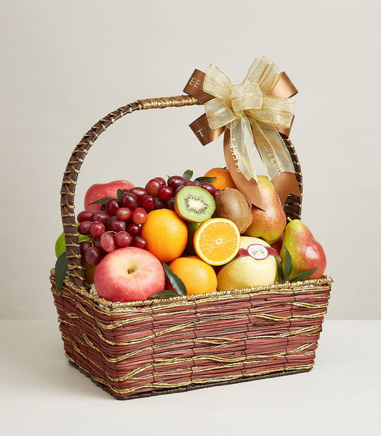 Dark brown wicker fruit basket with gold accents, filled with fresh grapes, apples, oranges, kiwis and pears, tied with gold