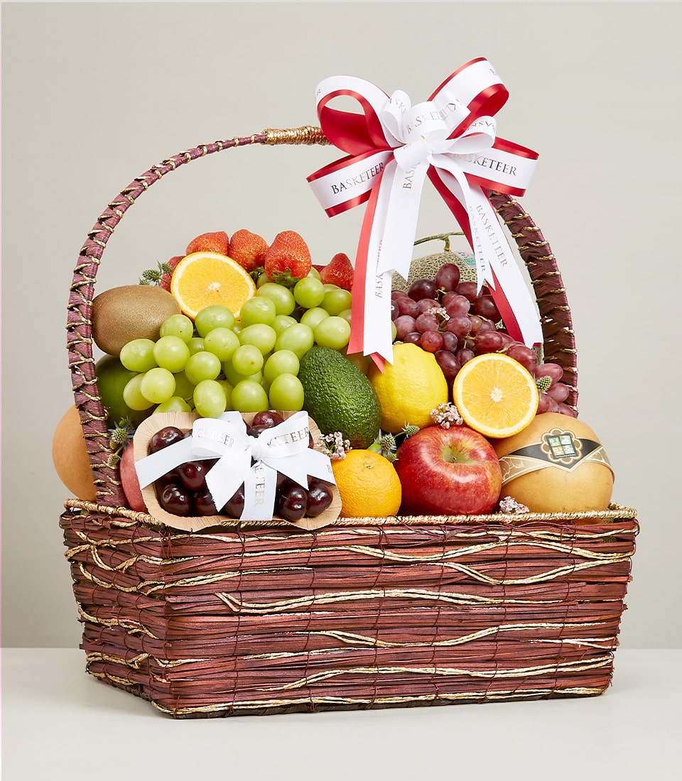Premium woven fruit hamper with fresh grapes, strawberries, citrus, and seasonal produce, gold-accented rattan basket with