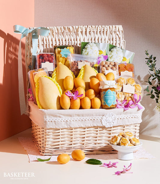 Woven wicker gift basket filled with Thai mangoes, Marian plums, preserves, nuts, and gourmet treats with purple orchids