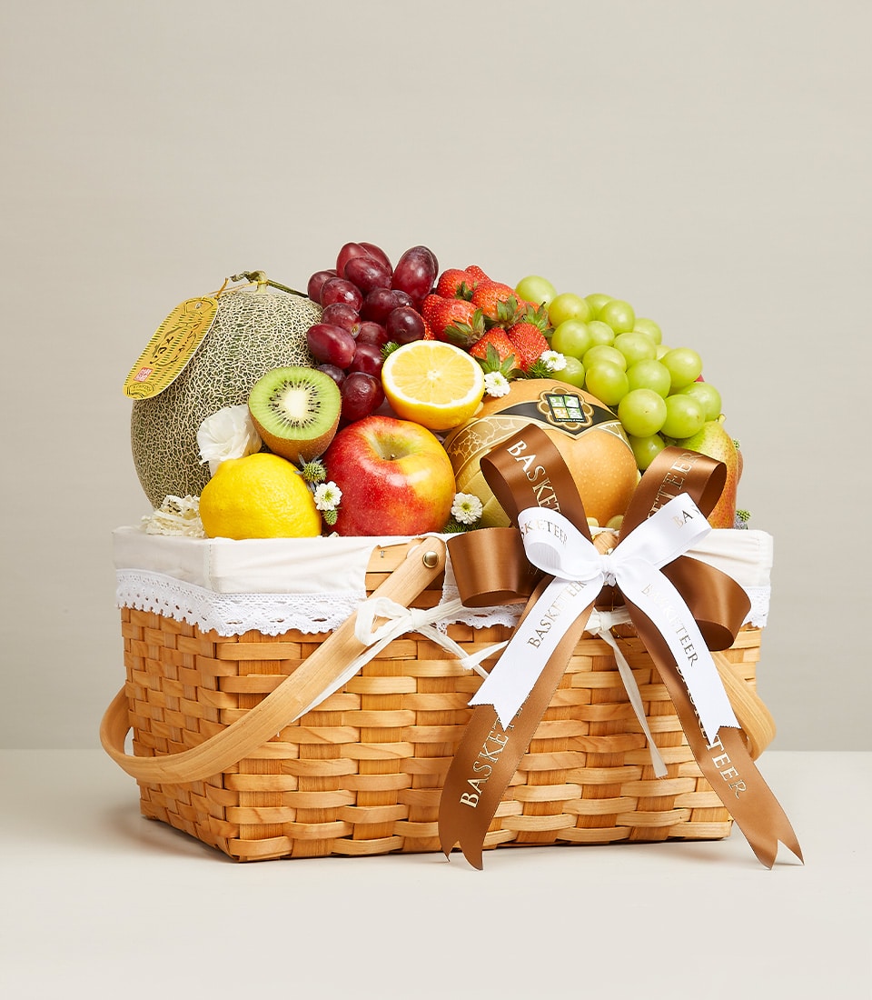 Woven fruit basket with fresh cantaloupe, grapes, strawberries, kiwi, apple and lemon for birthdays