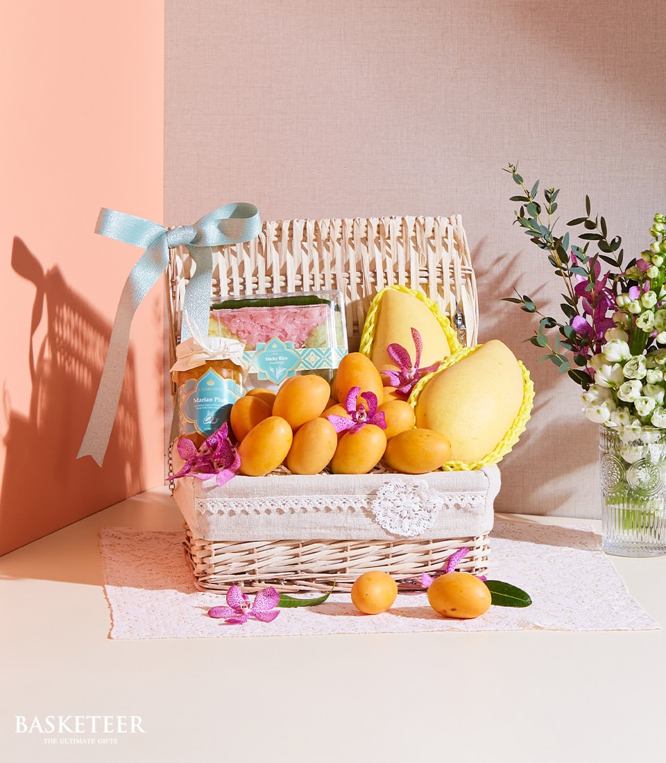 Wicker gift basket with Thai mango, plum preserve, pink sticky rice, and purple orchids