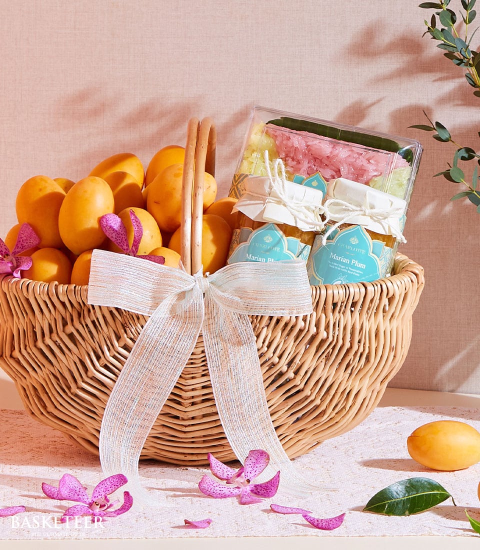 Woven wicker basket of fresh Marian plums with artisan sticky rice jars and purple orchids