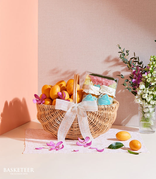 Woven gift basket with Marian plums, sticky rice sweets, orchids and white flowers on lace mat
