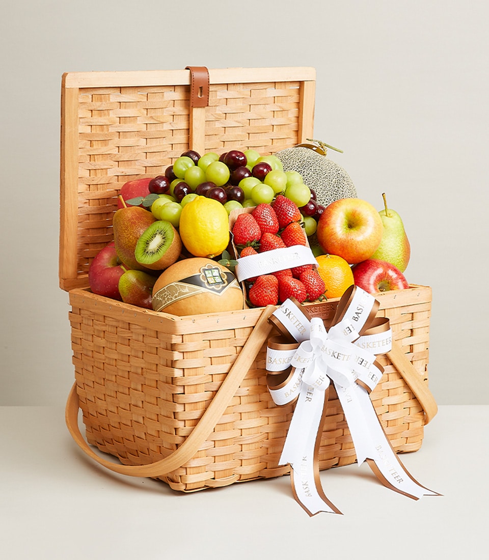 Premium wicker fruit basket with fresh grapes, strawberries, apples, pears and melon, tied with ribbon