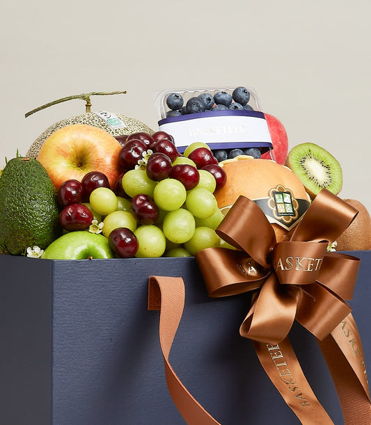 Luxury navy fruit gift bag with fresh cantaloupe, apples, avocado, grapes, cherries, blueberries and kiwi for birthday