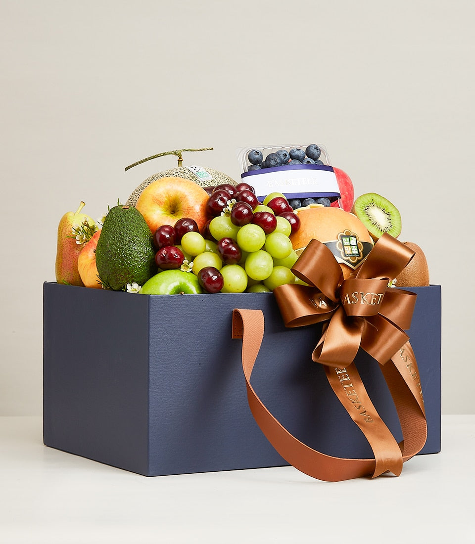Navy gift box with fresh fruit assortment, green grapes, cherries, apples, pear, kiwi and blueberries for birthday