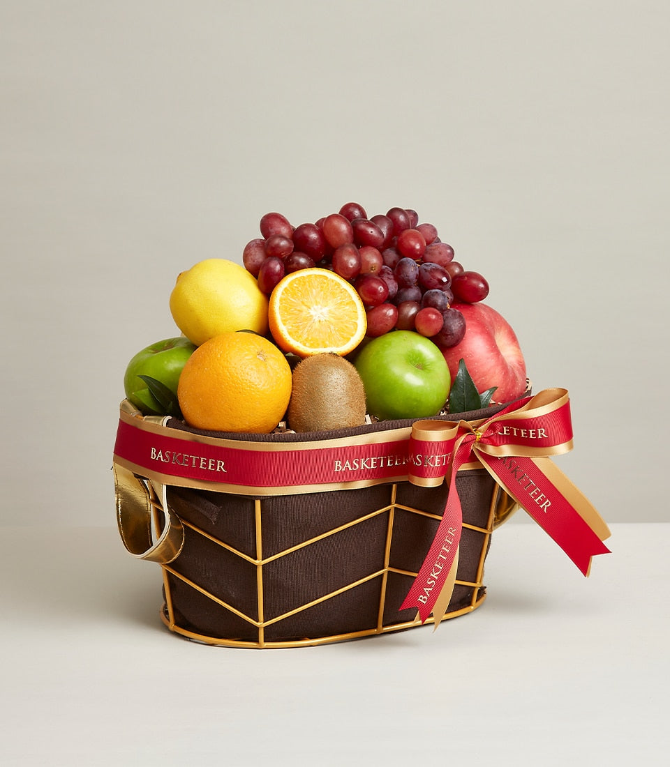 Dark brown fabric fruit basket with gold wire frame and handles, filled with fresh red grapes, green and red apples,