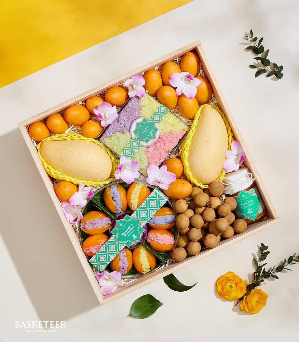 Thai summer fruits gift box with mangoes, longan, and Marian plums, artisan sticky rice, and fresh orchids