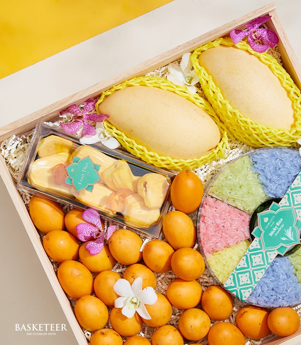 Wooden gift box with Thai mangoes, dried jackfruit, tropical fruits, and four-colour sticky rice in artisan presentation