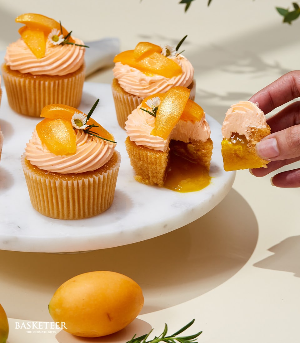 Mango cupcakes with fresh fruit topping and golden filling on marble stand