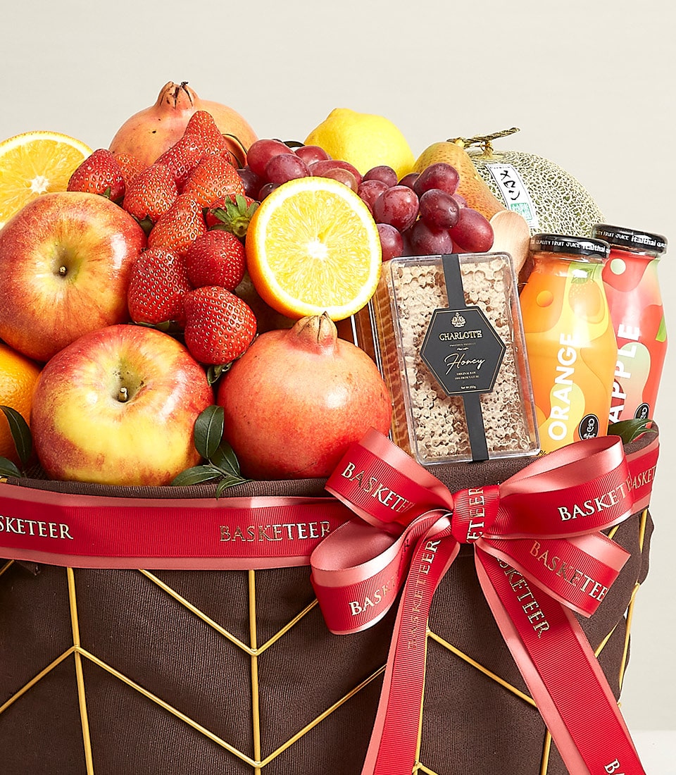 Basketeer premium hamper delivery in Bangkok: apples, pomegranates, honey and juice in a geometric basket tied with a branded red ribbon. A luxurious gift.