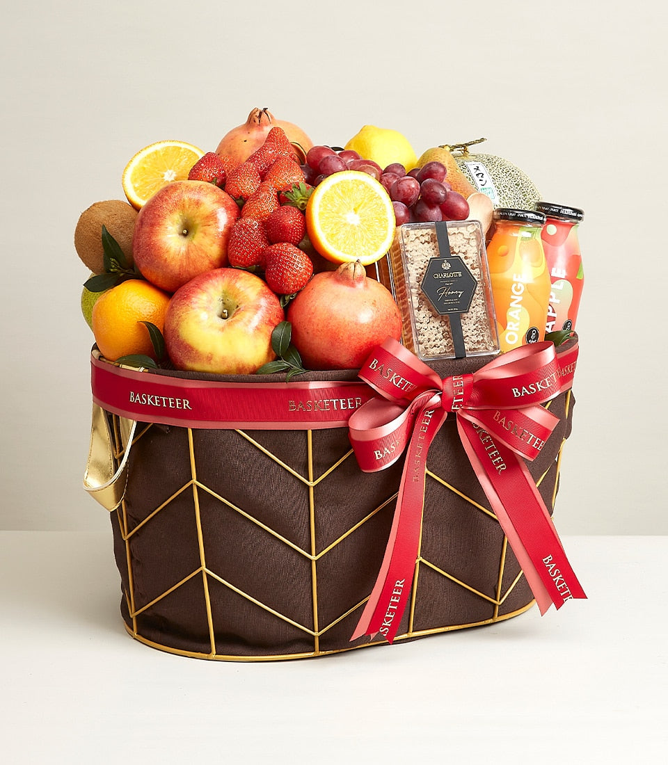 Luxury fruit and wellness gift basket with fresh apples, pomegranates, strawberries, organic juices and honey in
