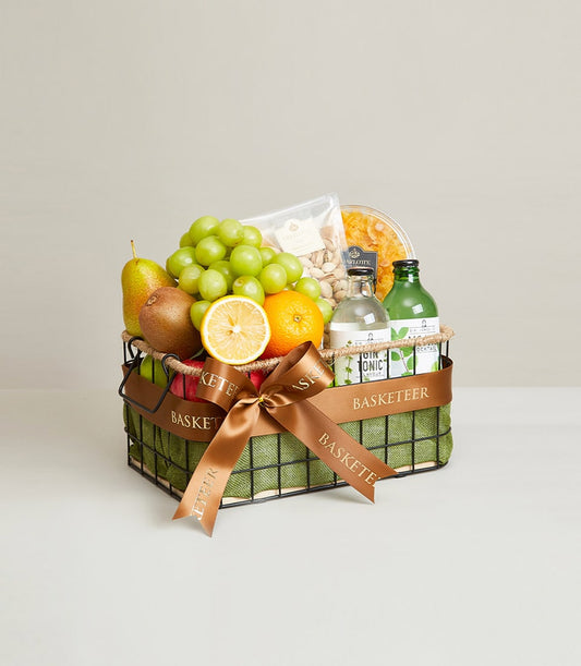 Premium black wire fruit basket with green grapes, pear, kiwis, orange, pistachios, and wellness products tied with brown
