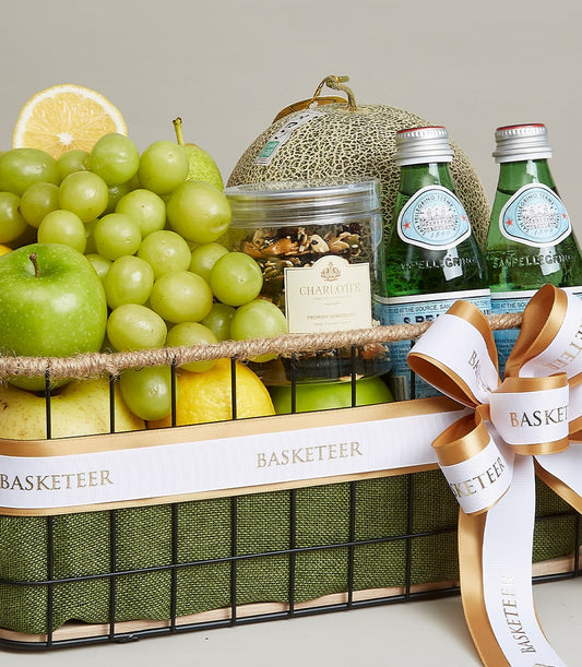 Nutrient-rich gourmet fruit basket with green grapes, apple, pear, cantaloupe, sparkling water, and Charlotte granola in