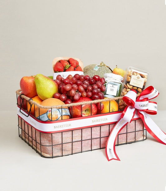 Luxury fruit and gourmet gift basket with apples, pears, grapes, strawberries, nuts, and artisan treats in black wire frame